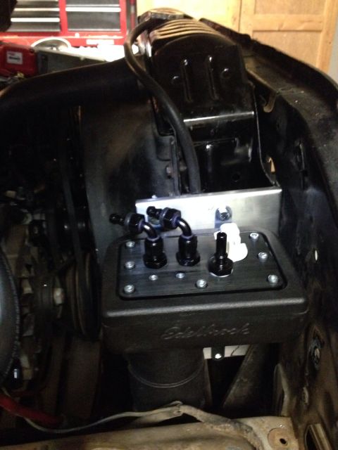 1978 Ford Bronco - Close-up of an engine bay showing a black Edelbrock fuel pump assembly with multiple black fittings and a white cap.