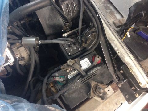 1978 Ford Bronco - Close-up view of engine bay components including a battery and fuel filter, with some parts covered by blue plastic.