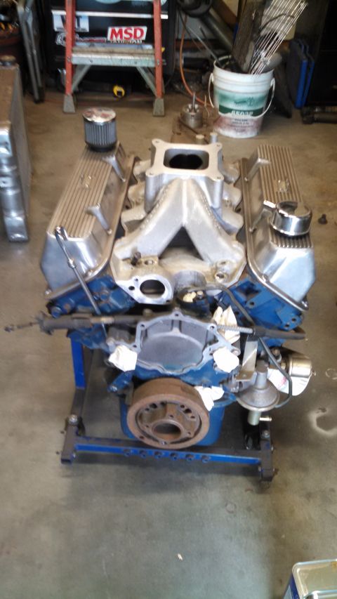 1988 Ford Bronco - A V8 engine with chrome valve covers and an aluminum intake manifold is displayed on a blue engine stand.