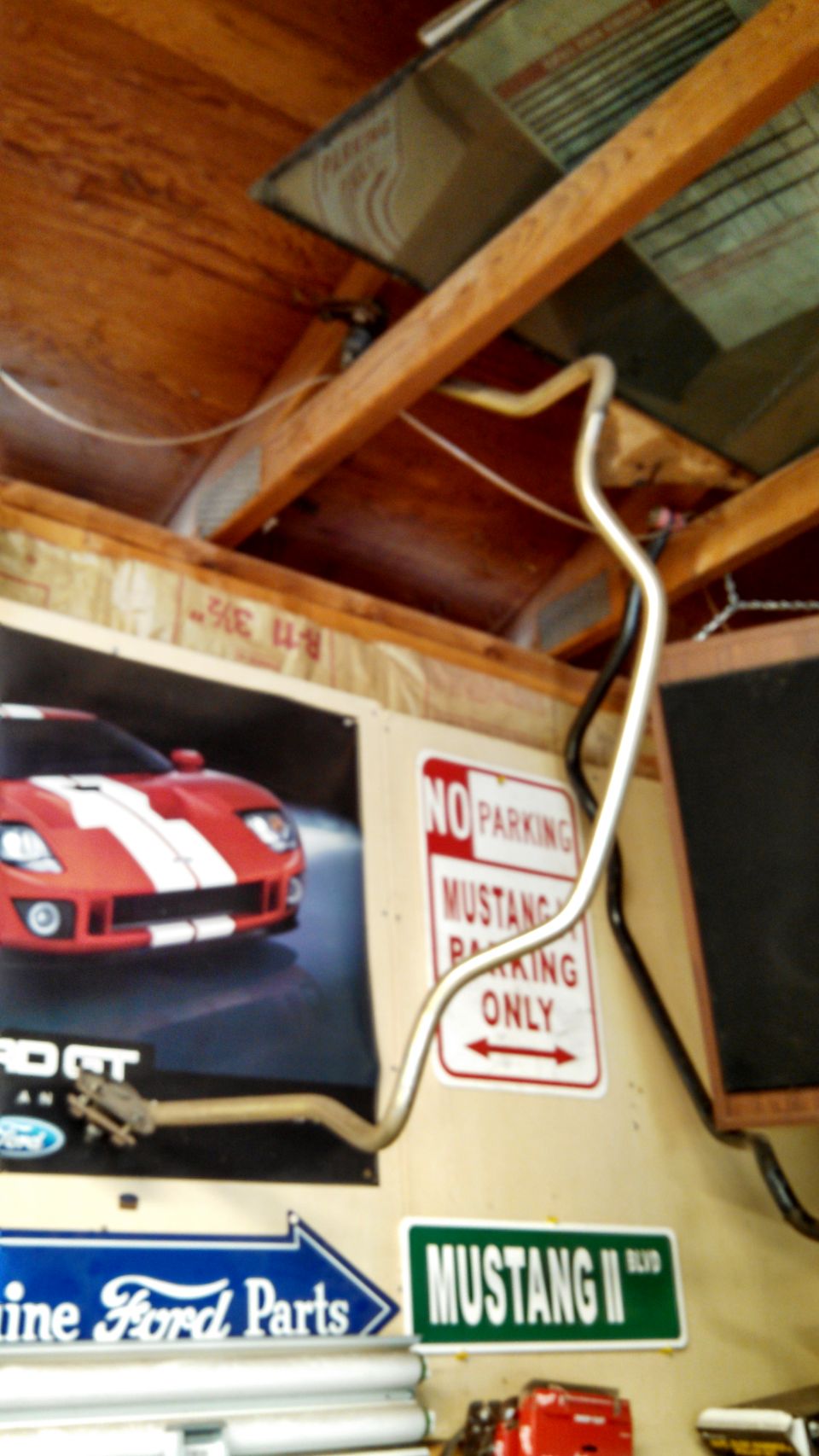 Metal pipe hanging from ceiling in garage with Ford and Mustang signs