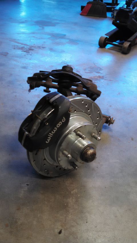 1988 Ford Bronco - A performance brake assembly, a Wilwood caliper and drilled rotor, rests on a garage floor.
