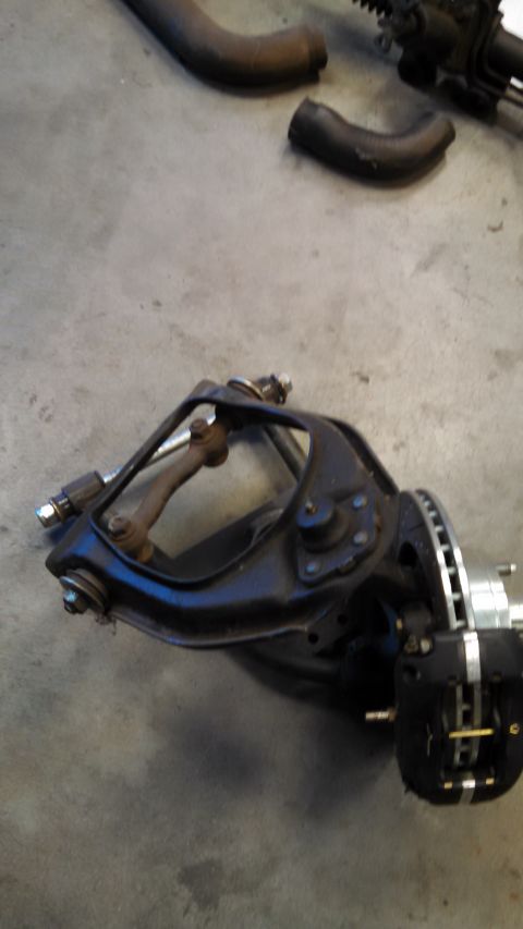 1988 Ford Bronco - A single automotive suspension component with a brake caliper and rotor is shown on a concrete surface.
