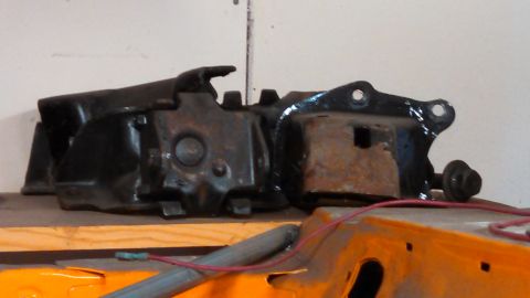 1988 Ford Bronco - A black metal automotive part, showing signs of rust, is displayed on a shelf.