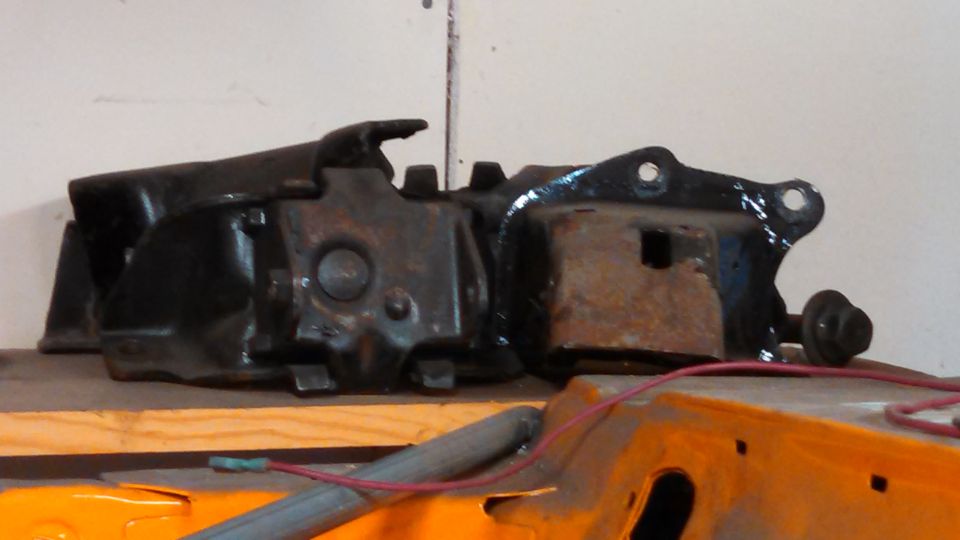 Black metal automotive part with rust and mounting holes
