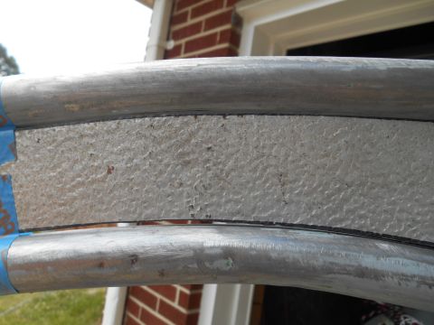 close-up of two metal pipes with a textured gray insert between them, held by blue tape