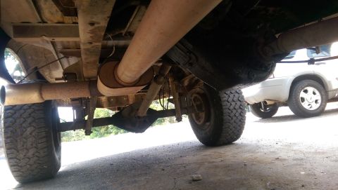 1976 Ford F-250 - The underside of a 1976 Ford F-250 pickup truck is visible, with another vehicle parked behind it.