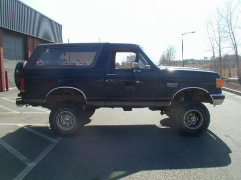 1988 Ford Bronco - Side profile of a lifted 1988 Ford Bronco, showing its off-road tires and suspension modifications.