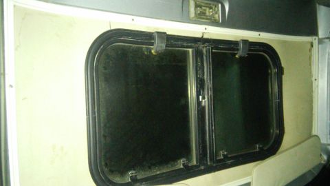 1979 Ford Bronco - Close-up view of the interior window of a vehicle, showing the black trim and latch mechanism.