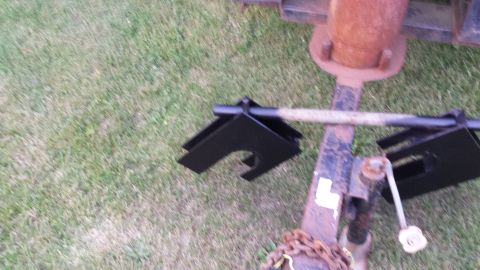 Trailer hitch attachment with black metal brackets and a rusty metal pole