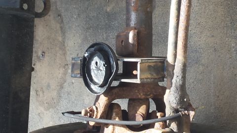 rusted vehicle suspension component with a black circular part attached