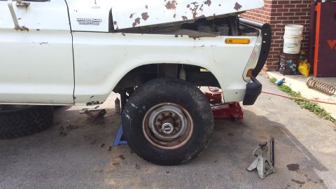White 1979 Ford Bronco with hood open, front wheel on jack stand