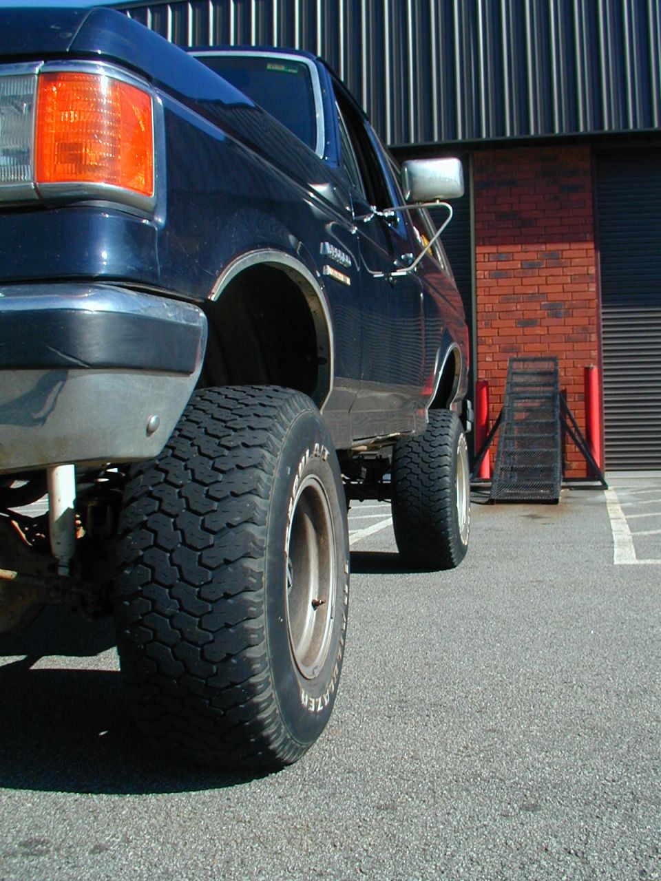 Dark blue 1988 Ford Bronco with lifted suspension and large tires, viewed from the front quarter