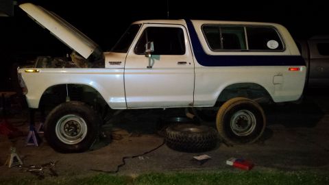 White 1979 Ford Bronco side view, hood open, on jacks with spare tire