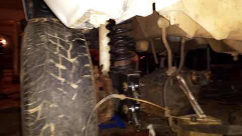 Close-up of a vehicle's front tire and suspension components, possibly undergoing maintenance