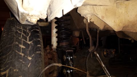 Undercarriage view of a vehicle's tire and black coil spring suspension