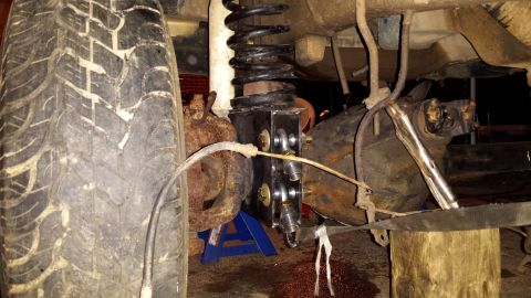 Close-up of vehicle's rear suspension with tire, coil spring, and differential visible