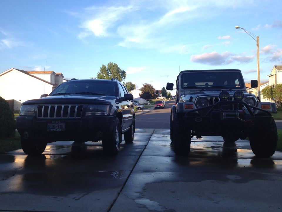 Black 2004 Jeep Grand Cherokee parked next to a modified Jeep Wrangler, front view