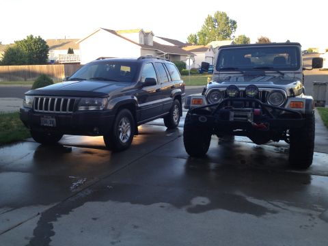 2004 Jeep Grand Cherokee - A dark 2004 Jeep Grand Cherokee is parked in a driveway next to a modified Jeep Wrangler.