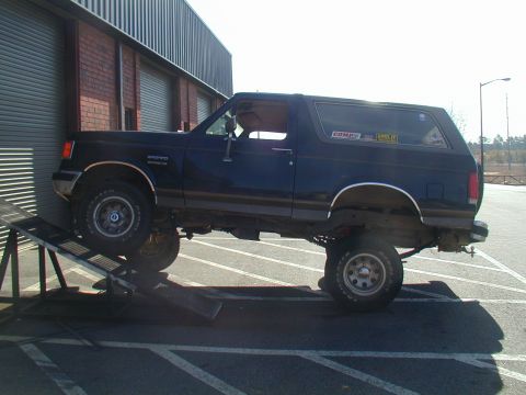 1988 Ford Bronco - A lifted Ford Bronco is positioned on a ramp, with its front end raised higher than the rear.