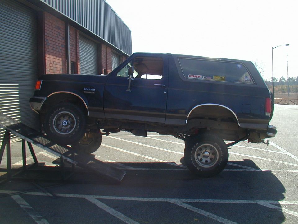 Dark blue Ford Bronco on a metal ramp, front wheels elevated