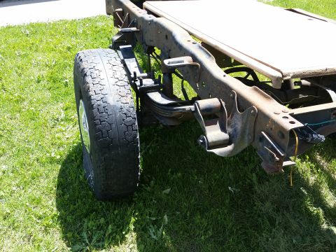 1988 Ford Bronco - The rear suspension and frame of a truck are visible, with a tire on the left side.