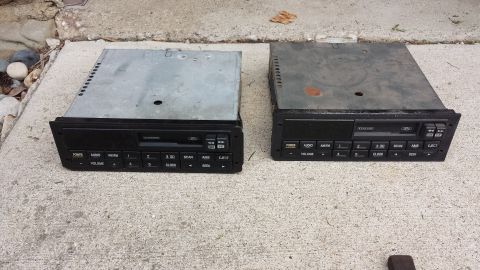 1995 Ford Bronco - Two Ford car radios are shown on a concrete surface. One appears to be in better condition than the other.