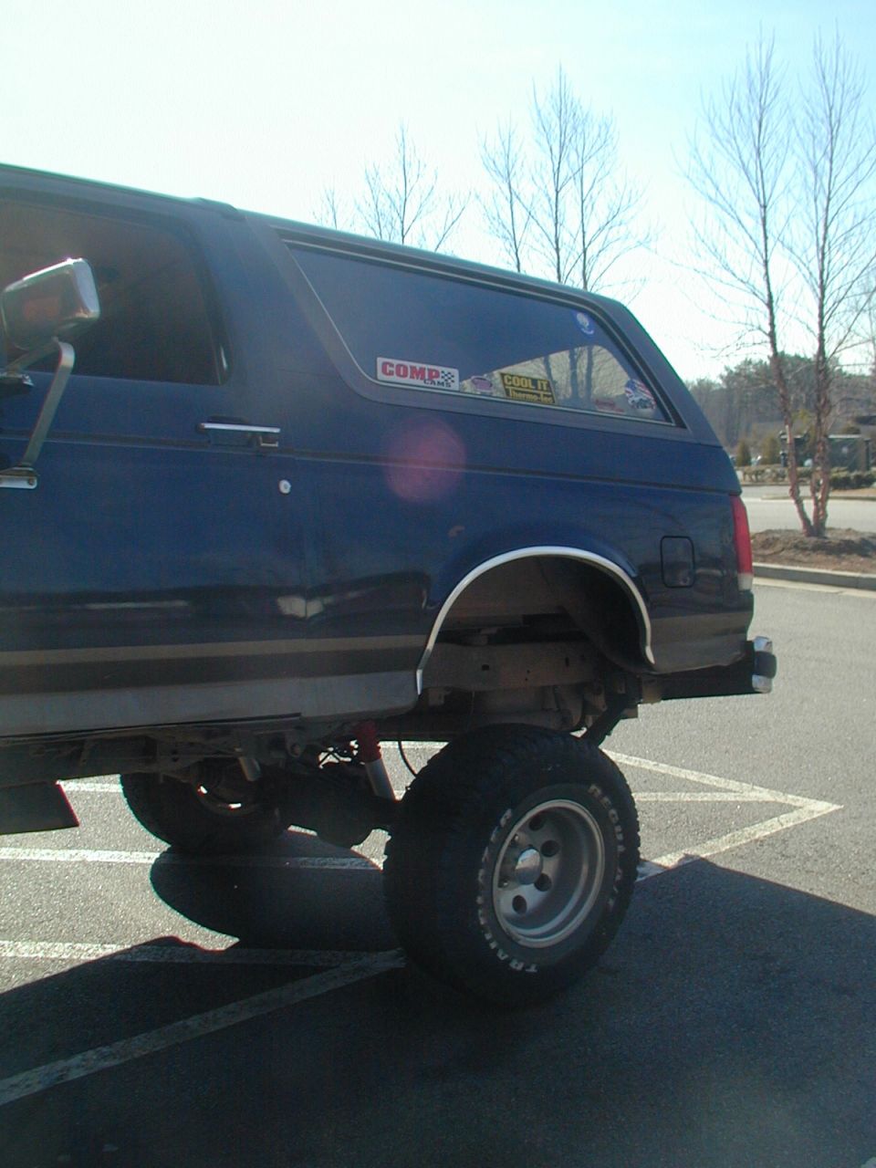 Dark blue Ford Bronco lifted with large tires, seen from the rear quarter angle