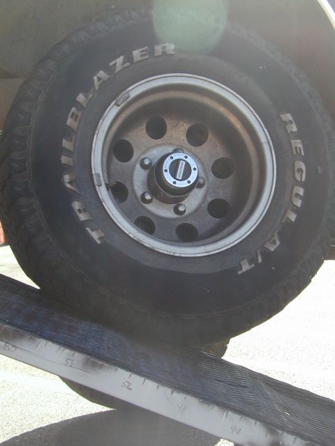 1988 Ford Bronco - A close-up view of a tire and wheel assembly, "Trailblazer" and "Regular A/T" text, is positioned on a ramp.
