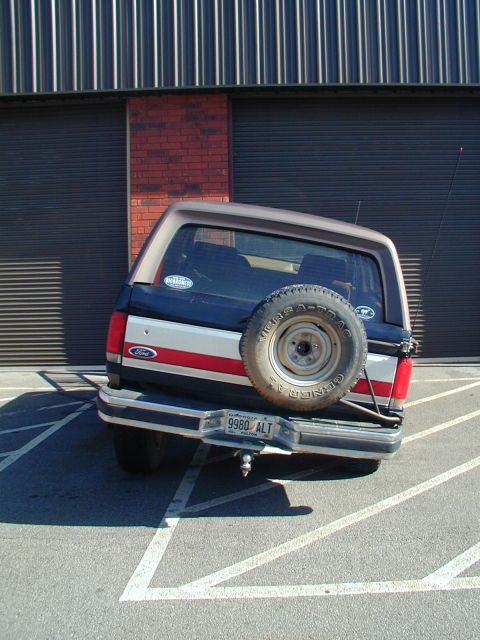 1988 Ford Bronco - This Ford Bronco is parked in a lot with a large garage door in the background.