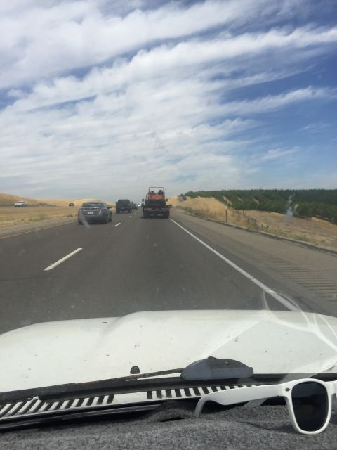 1946 Jeep Willys - View from inside a white vehicle looking out at a highway with other cars and trucks. A pair of white sunglasses rests on the dashboard in…