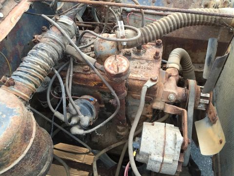 1946 Jeep Willys - A close-up view of a heavily rusted engine bay, likely from an older vehicle, showing various components like hoses, wires, a distributor c…