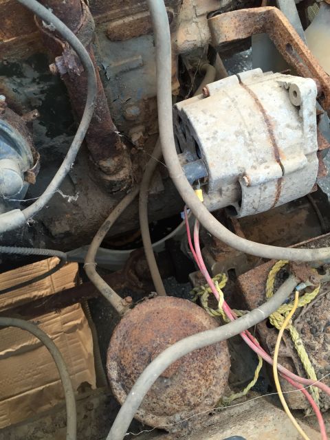 1946 Jeep Willys - This is a close-up view of an old, rusty engine bay with an alternator and various wires and hoses. The engine components are heavily corro…