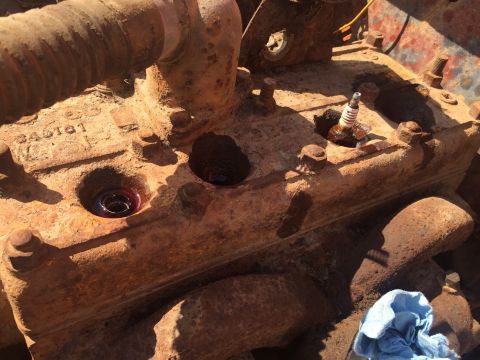 1946 Jeep Willys - A close-up view of a heavily rusted engine block with a spark plug visible in one cylinder and a dark liquid in another.