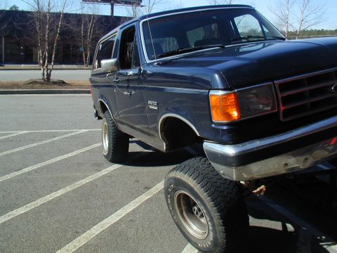 1988 Ford Bronco - Ford Bronco with lifted suspension parked in a lot.