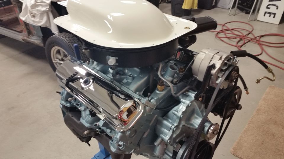 Rebuilt Pontiac V8 engine with chrome valve covers and white air cleaner assembly on an engine stand.