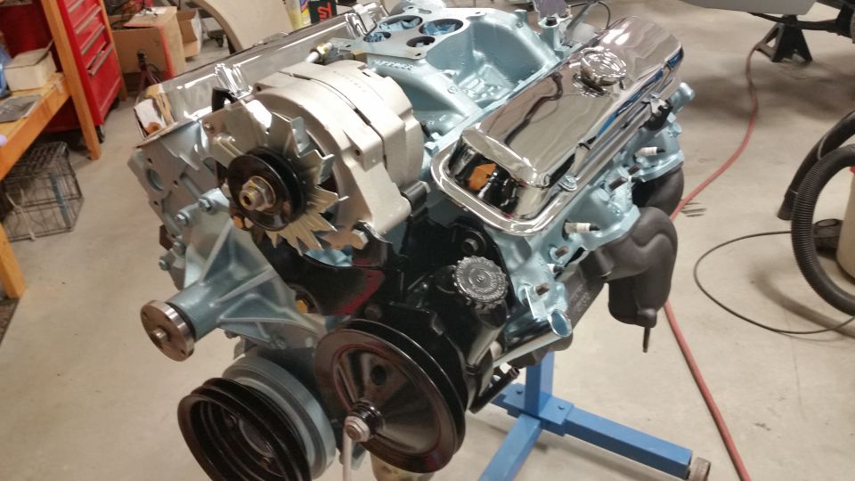Light blue V8 engine with chrome valve covers on a blue stand, front-right quarter view.