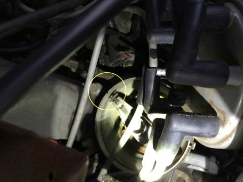 1989 Ford Bronco - A close-up view of the engine bay shows a distributor cap with spark plug wires attached. A yellow circle highlights a bolt on the side of…