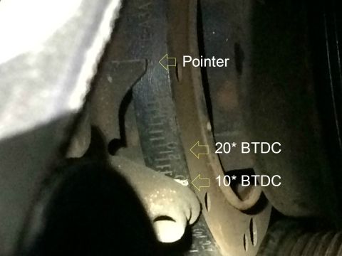 1989 Ford Bronco - A close-up view of an engine timing mark pointer aligned with the 20° BTDC mark on a scale. The pointer is labeled, and the scale shows 10°…