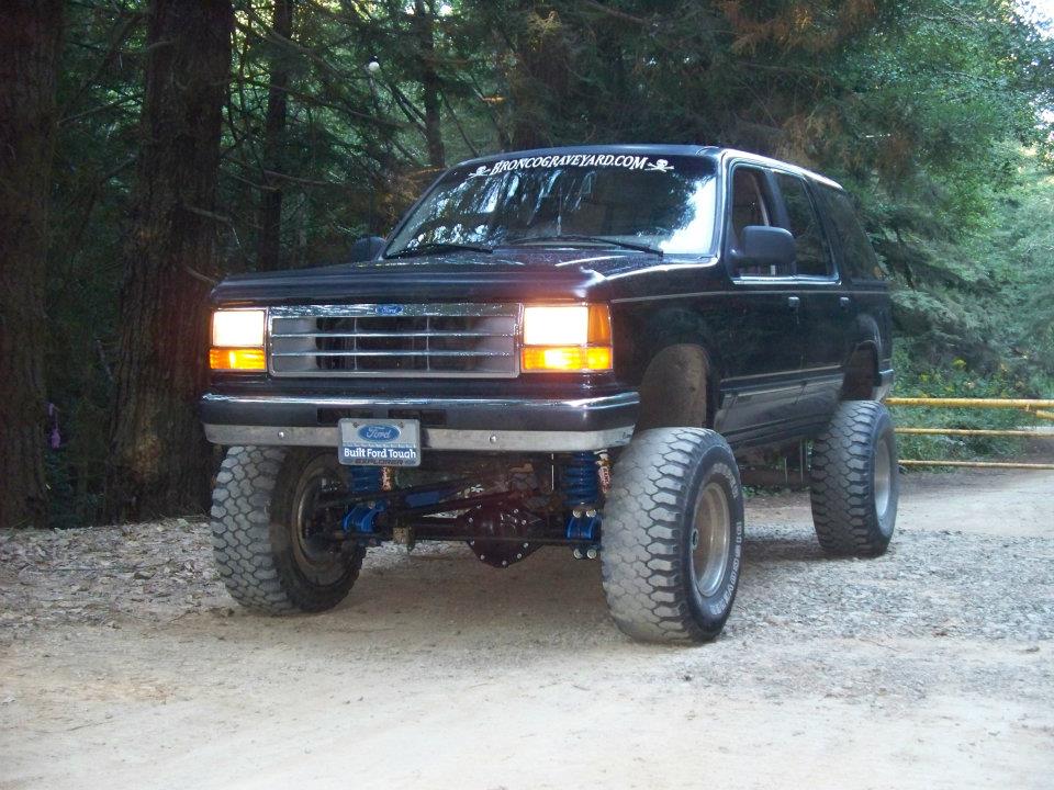 Lifted black Ford Explorer with large off-road tires and "Built Ford Tough" plate.