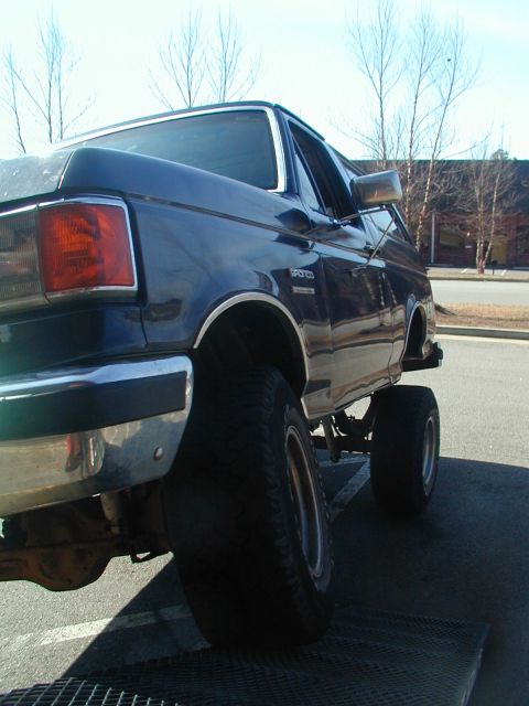 1988 Ford Bronco - This lifted 1988 Ford Bronco is positioned on a ramp, its large tires and off-road capabilities.