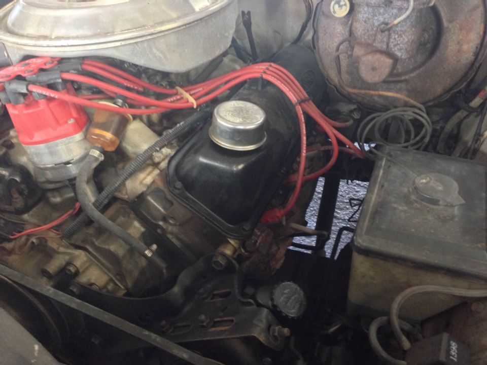 Close-up of a vehicle engine bay with red distributor cap and spark plug wires.