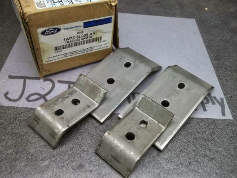 1999 Mercury Grand Marquis - A Ford trailing arm kit is shown with its original packaging. The kit includes several metal brackets with holes for mounting.