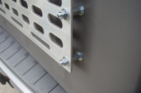 2005 Toyota 4Runner - A close-up view shows a silver perforated metal panel bolted to a dark gray panel, likely part of a vehicle's cargo area. The metal panel h…