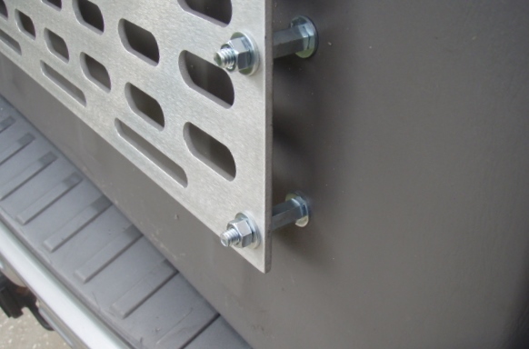 Silver perforated metal panel with oval cutouts bolted to a dark gray panel.