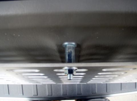 2005 Toyota 4Runner - A close-up view shows two bolts securing a perforated metal plate to a dark textured surface, likely part of a vehicle's undercarriage or c…