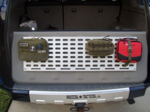 2005 Toyota 4Runner - The rear cargo area of a dark blue SUV features a silver perforated panel mounted on the tailgate. Three pouches are attached to the panel:…