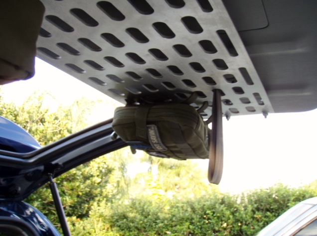 Interior of a vehicle showing a metal storage rack with a green pouch hanging from it.