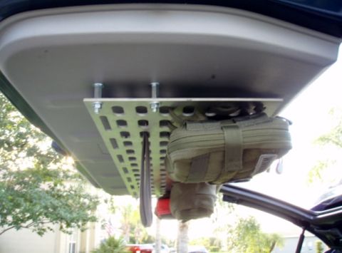 2005 Toyota 4Runner - A metal MOLLE panel is mounted to the underside of a vehicle's tailgate, holding a tan pouch and a dark-colored tool. The panel is secured…
