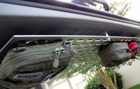 2005 Toyota 4Runner - A perforated aluminum MOLLE-style panel mounted to the underside of an open SUV liftgate, hung with olive drab pouches — one with a 'WINNIN…