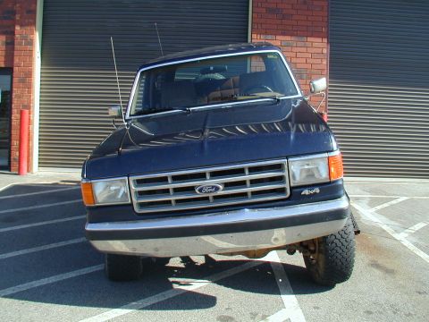 1988 Ford Bronco - Front view of a dark blue 1987 Ford Bronco parked in front of a garage door.